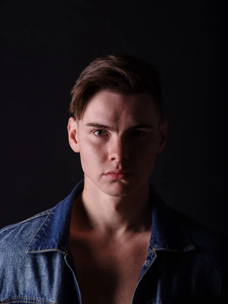 Close-up menino adolescente bonito em um casaco de jeans em um fundo preto. Corte de cabelo masculino e conceito de estilo . — Fotografia de Stock