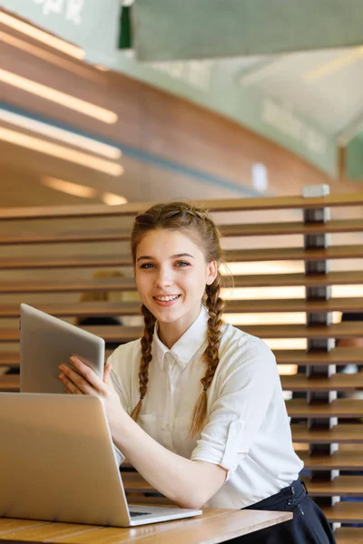 A garota atrás do laptop está sentada em um café — Fotografia de Stock