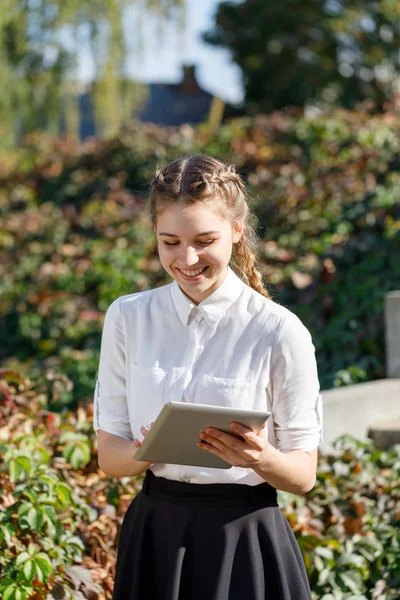 Ung flicka i parken med en tablett i hand. — Stockfoto