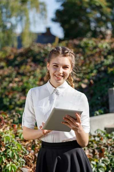 Ung flicka i parken med en tablett i hand. — Stockfoto
