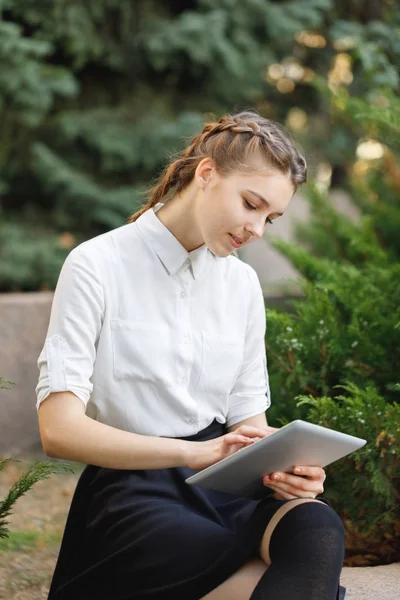 Bir tablet ile bir parkta genç esmer kız oturuyor. — Stok fotoğraf