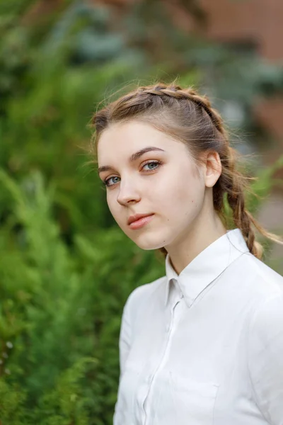 Vacker ung flicka promenader i parken på bakgrunden av fir grenar. — Stockfoto