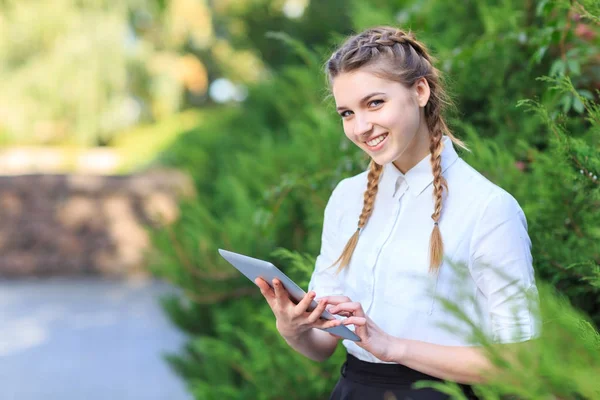 Bir tablet ile bir parkta genç esmer kız oturuyor. — Stok fotoğraf