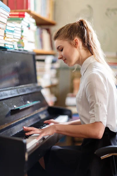 Young woman in a white blouse playing the piano