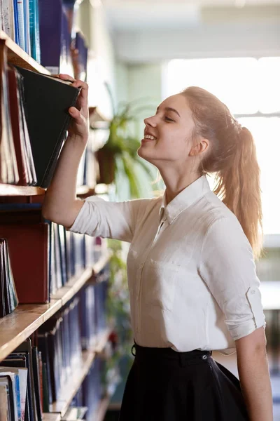 Студент берет книгу с полки в библиотеке . — стоковое фото