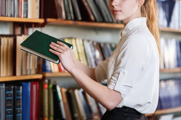 Bir kitap bir raf kütüphanede alarak bir öğrenci. — Stok fotoğraf