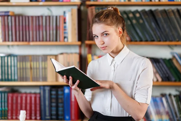 Porträt eines jungen Mädchens, das in der Bibliothek ein Buch liest. — Stockfoto