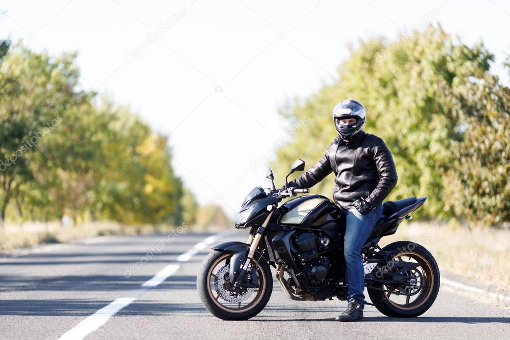A close-up of a motorcycle stands on the road with its owner alone