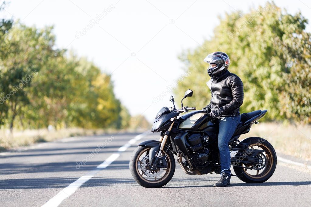 A close-up of a motorcycle stands on the road with its owner alone