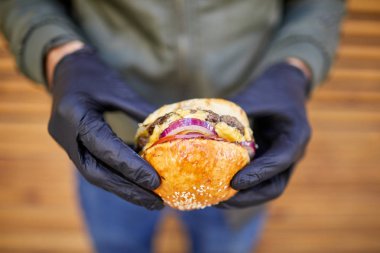 Ahşap arka plan üzerinde erkek elinde sığır eti ile Juisy burger. Gıda kavramı.