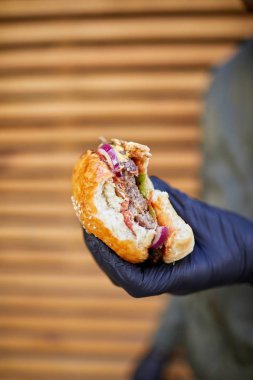 Ahşap arka plan üzerinde erkek elinde sığır eti ile Juisy burger. Gıda kavramı.