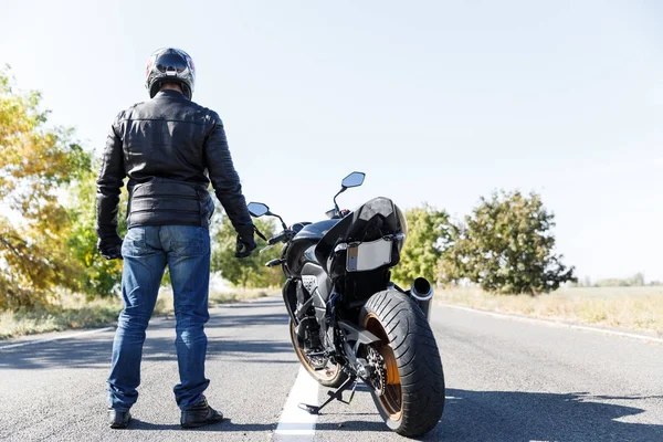 Um close-up de uma motocicleta fica na estrada com seu proprietário sozinho — Fotografia de Stock