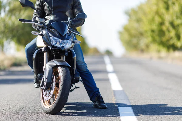 Крупный план мотоцикла стоит на дороге с его владельцем в одиночку — стоковое фото