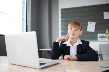 Bir dizüstü bilgisayar bir ofiste arkasında masaüstünde çalışan küçük bir iş kadını