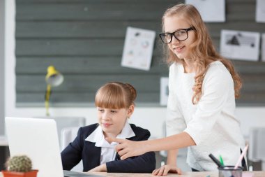 A small businesswoman works at a computer and is helped by an employee clipart