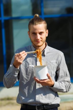 Çin eriştesi kutusunda karides, sebze ve Soya soslu susam ile yakışıklı adam. Gıda kavramı.