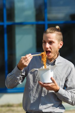 Çin eriştesi kutusunda karides, sebze ve Soya soslu susam ile yakışıklı adam. Gıda kavramı.