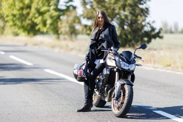 Dziewczyna siedzi na motocyklu w czarne skórzane ubrania — Zdjęcie stockowe