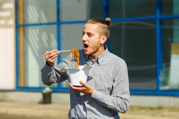 Hombre guapo con fideos chinos en caja con camarones, verduras y sésamo con salsa de soja. Concepto alimenticio . —  Fotos de Stock