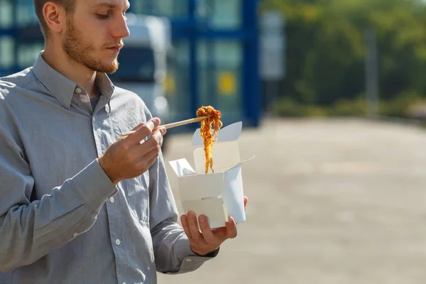 Hombre guapo con fideos chinos en caja con camarones, verduras y sésamo con salsa de soja. Concepto alimenticio . —  Fotos de Stock