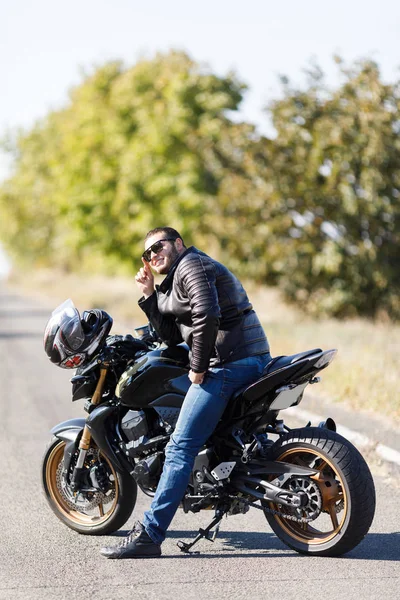 Um close-up de uma motocicleta fica na estrada com seu proprietário sozinho — Fotografia de Stock