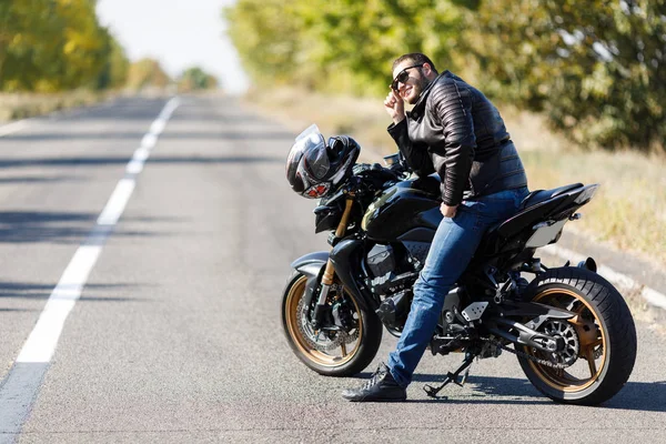 Um close-up de uma motocicleta fica na estrada com seu proprietário sozinho — Fotografia de Stock