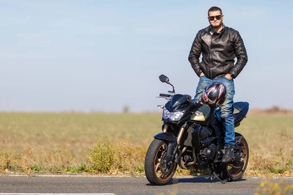 Красивый мотоцикл стоит на дороге в одиночестве со своим владельцем — стоковое фото