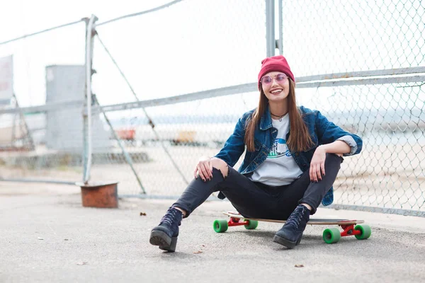 Красивая девушка сидит на скейтборде на природе . — стоковое фото
