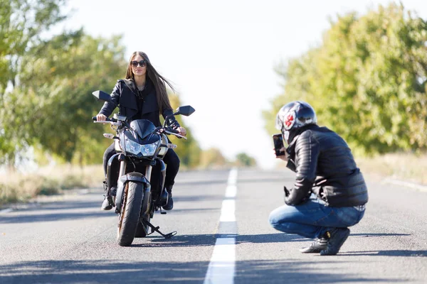 Мотоциклист наблюдает, как его девушка ездит на велосипеде — стоковое фото