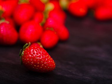 Koyu ahşap bir masa üzerinde tatlı taze çilek. Gıda kavramı.