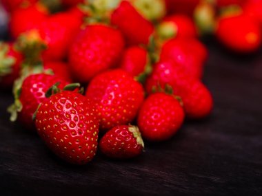 Koyu ahşap bir masa üzerinde tatlı taze çilek. Gıda kavramı.