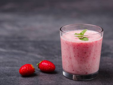 Gri bir arka plan üzerine bir bardak tatlı taze çilek jogurt. Gıda kavramı.