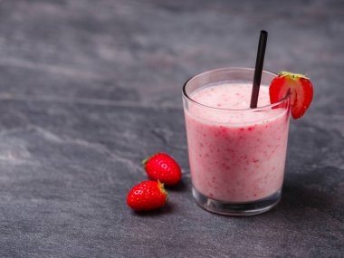 Gri bir arka plan üzerine bir bardak tatlı taze çilek jogurt. Gıda kavramı.