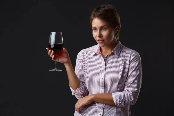 Schönes Mädchen mit einem Glas Rotwein auf schwarzem Hintergrund. — Stockfoto