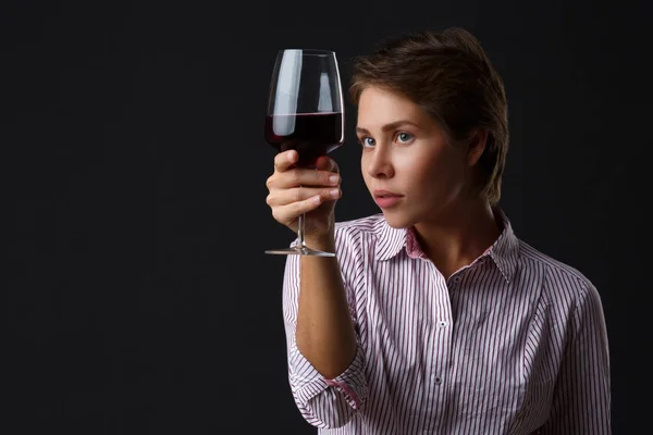 Piękna dziewczyna z kieliszkiem czerwonego wina na czarnym tle. — Zdjęcie stockowe