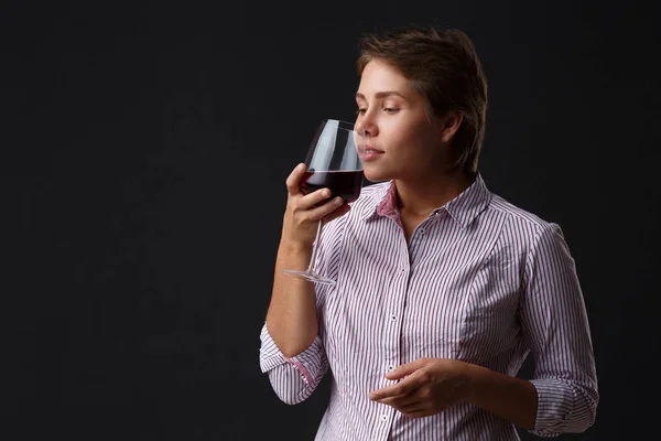 Красива дівчина з келихом червоного вина на чорному тлі . — стокове фото