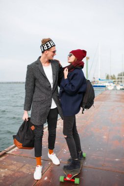 Pier girl on kız adamla kaykay üzerinde sürme