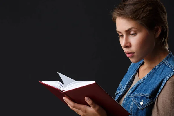 Привлекательная девушка с красной книгой на черном фоне — стоковое фото