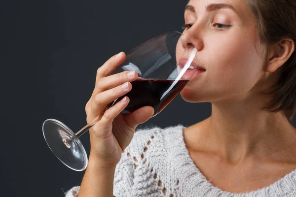 Bella ragazza con un bicchiere di vino rosso su uno sfondo nero . — Foto Stock