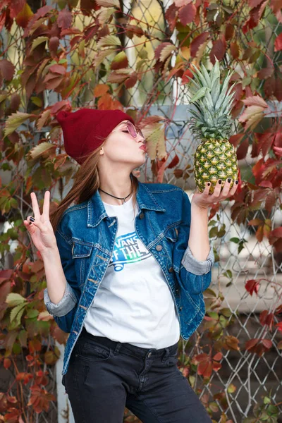 Egy lány egy ananász áll az utcán egy őszi háttér — Stock Fotó