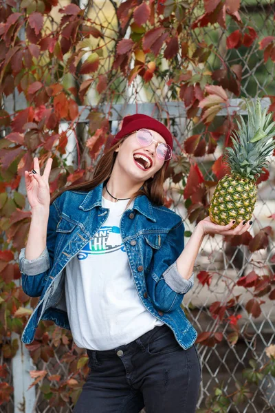 Bir kız bir ananas ile sonbahar bir arka plan üzerinde sokakta duruyor — Stok fotoğraf