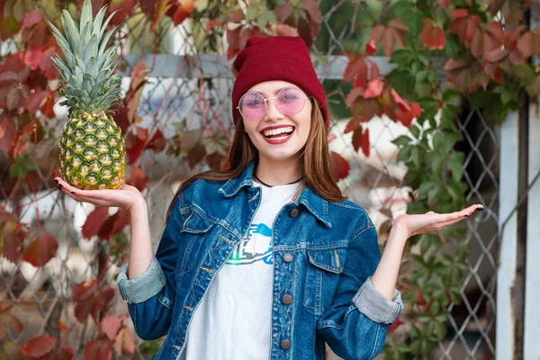 Een meisje met een ananas is permanent op de straat op een herfst achtergrond — Stockfoto