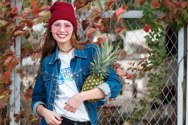 Egy lány egy ananász áll az utcán egy őszi háttér — Stock Fotó