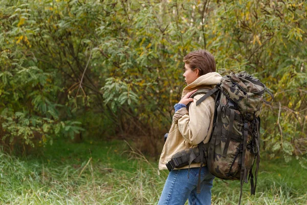 Junge Touristin, die mit einem großen Rucksack auf dem Rücken durch den Wald geht. — Stockfoto