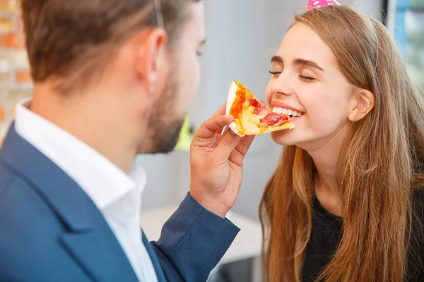 Un hombre está alimentando a una chica con un pedazo de pizza. . —  Fotos de Stock
