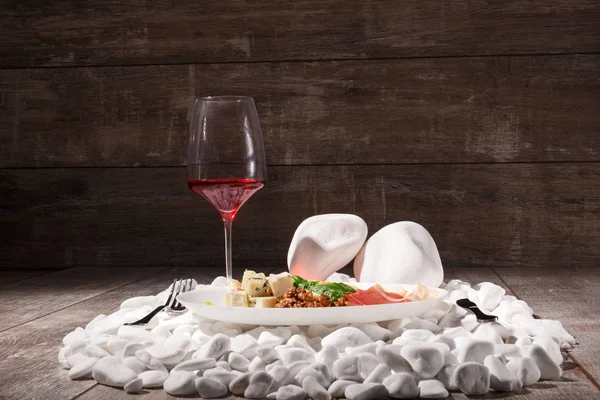 一杯红酒和餐厅午餐的豪华组合 在一堆白色岩石上的盘子里 白芝士配有刀叉的棕色木制背景 — 图库照片