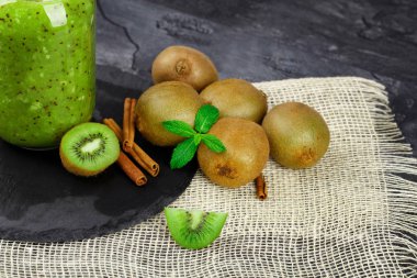 Güzel, taze, besleyici kivi meyve nane yaprakları ve siyah bir arka plan aromatik tarçın ile yakın çekim bir resim. Tropikal meyve yanındaki cam kavanozda bir vejetaryen kokteyl.