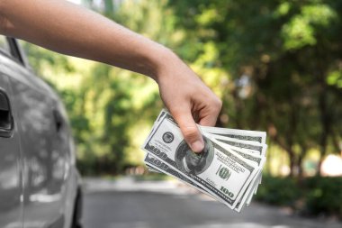 Yeni bir araba ve bir sürü Amerikan Doları bir bulanık yaz park arka plan üzerinde tutan bir insanın yakın çekim. Usds ile kurumsal bir iş adamı. Yatırım, tasarruf, mali kavramı. 