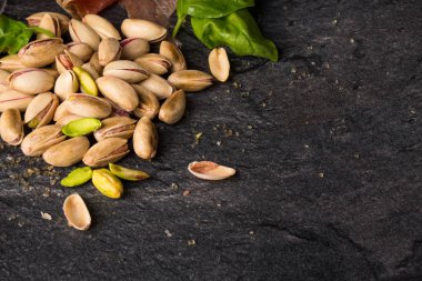 Siyah bir zemin üzerine üstten görünüm bir yığın kırık Antep fıstığı ve yeşil ıspanak. Geleneksel aperatifler ve mezeler. Tuzlu hafif kahverengi fıstık için fındık bir pub ya da bar. Kopya alanı.