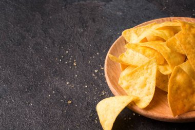 Altın cips cips hafif ahşap plaka üzerinde bir görünüm yukarıdan. Baharatlı lezzetli aperatifler alkollü içecekler için. Meksika geleneksel meze doygun siyah taş zemin. Kopya alanı.